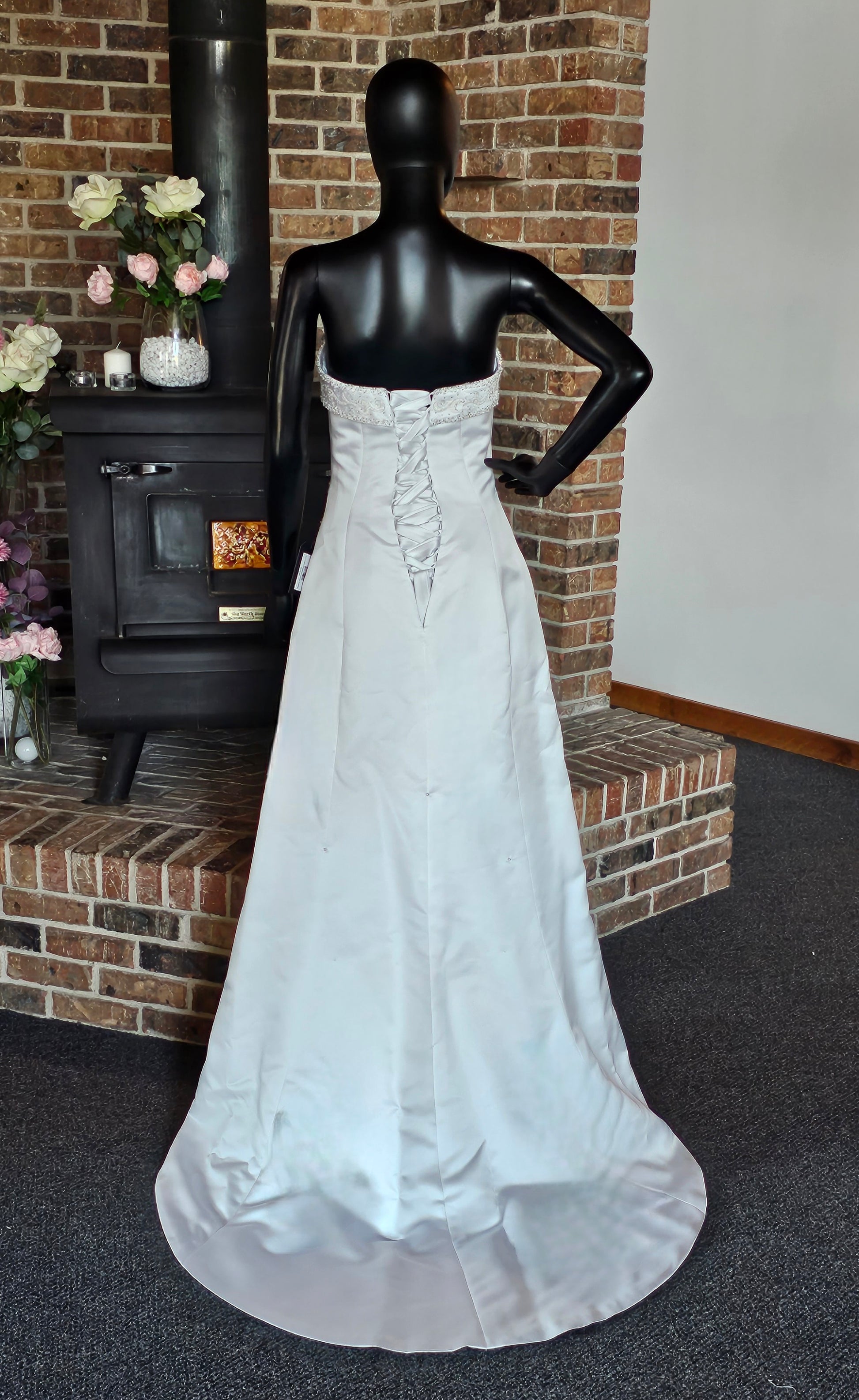 Maggie Sottero Wedding Gown  This gorgeous designer gown features a straight, banded neckline with lots of beads and embroidery. The asymmetrical side sweep adds interest and creates a lovely waistline. The creamy white satin is lustrous and falls to a small sweep train.   This gown is part of our consignment collection and has been worn before and slightly altered. It is in excellent condition and is ready to be loved again! 